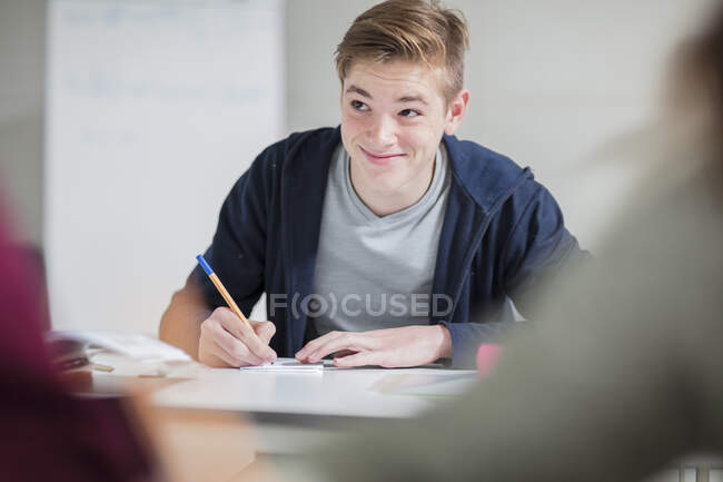 Lächelnder Teenager macht sich Notizen im Unterricht — Stockfoto