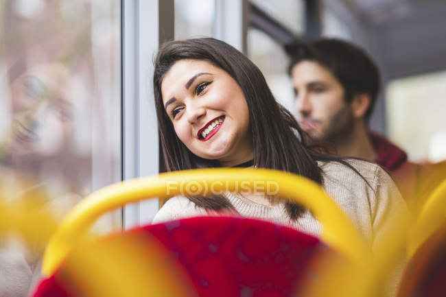 UK, Londra, ritratto di una giovane donna sorridente in autobus che guarda fuori dalla finestra — Foto stock
