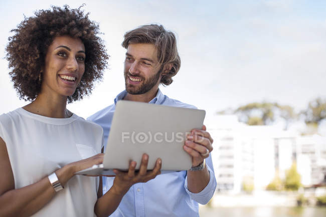 Empresario y mujer teniendo una reunión al aire libre, utilizando el ordenador portátil - foto de stock