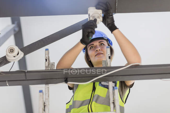 Jovem eletricista feminino instalando lâmpada — Fotografia de Stock