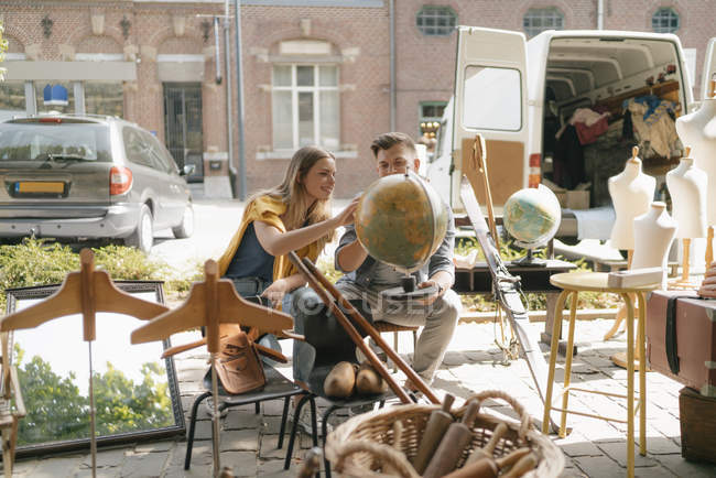 Bélgica, Tongeren, pareja joven examinando el mundo en un mercado de pulgas antiguas - foto de stock
