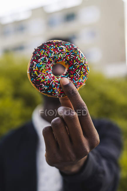 Jovem negro segurando um biscoito de chocolate — Fotografia de Stock