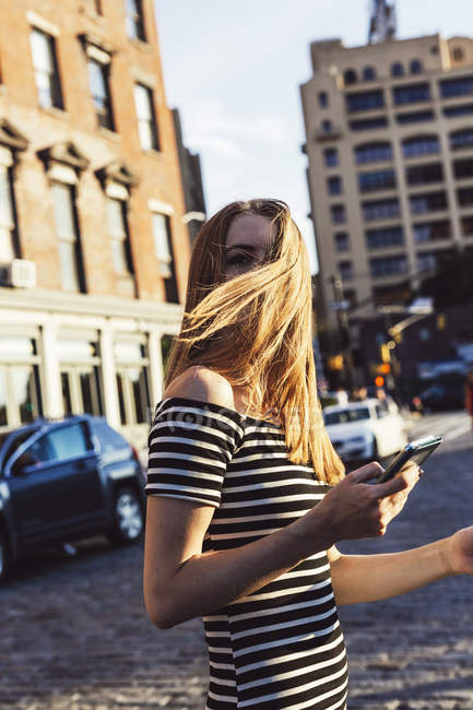 США, Нью-Йорк, Бруклин, Дамбо, женщина с мобильным телефоном, переходящая улицу — стоковое фото