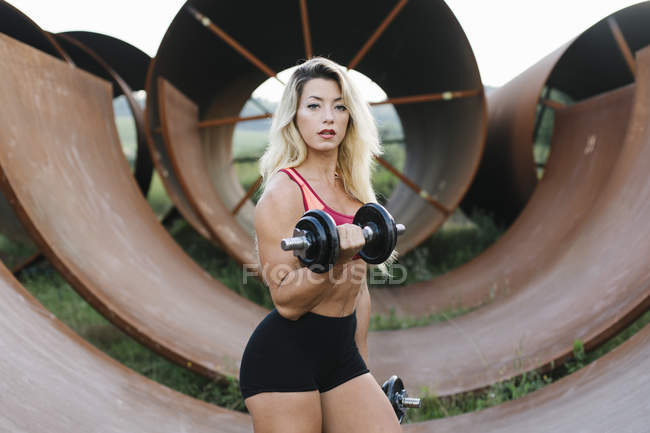 Mujer atlética haciendo ejercicio de peso en el sitio industrial - foto de stock