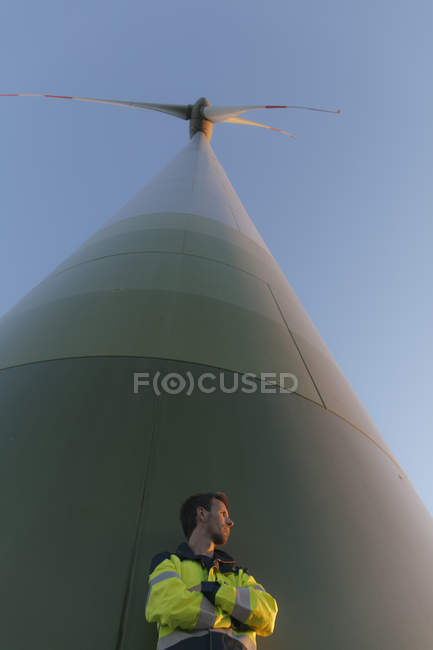 Низький кут зору інженера, що стоїть на вітровій турбіні — стокове фото