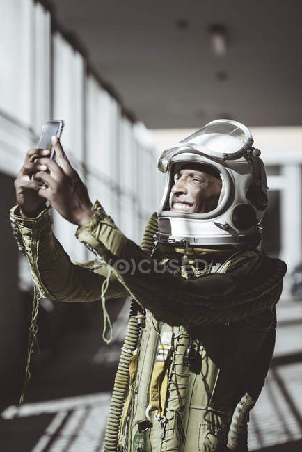 Astronauta feliz em spacesuit usando smartphone — Fotografia de Stock