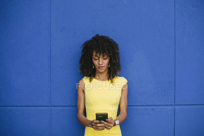 Retrato de mujeres de negocios de moda con mensajes de texto de vestimenta amarilla sobre fondo azul - foto de stock