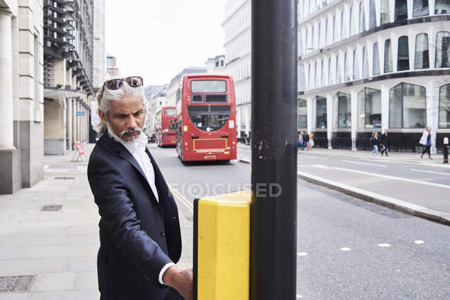 UK, London, bearded senior businessman pressing traffic lights button — Stock Photo
