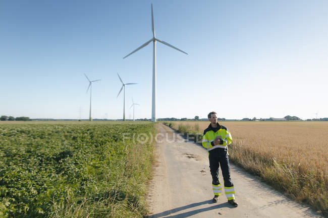 Ingeniero parado en una pista de campo en un parque eólico - foto de stock