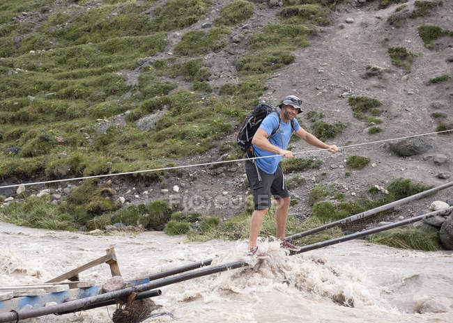 Russia, Caucaso, Alpinista che attraversa il fiume nell'Alta Valle di Baksan — Foto stock