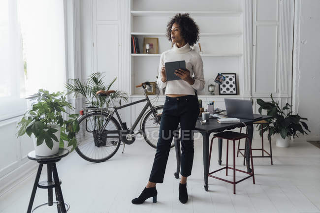 Freelance in piedi nel suo ufficio di casa, utilizzando tablet digitale — Foto stock