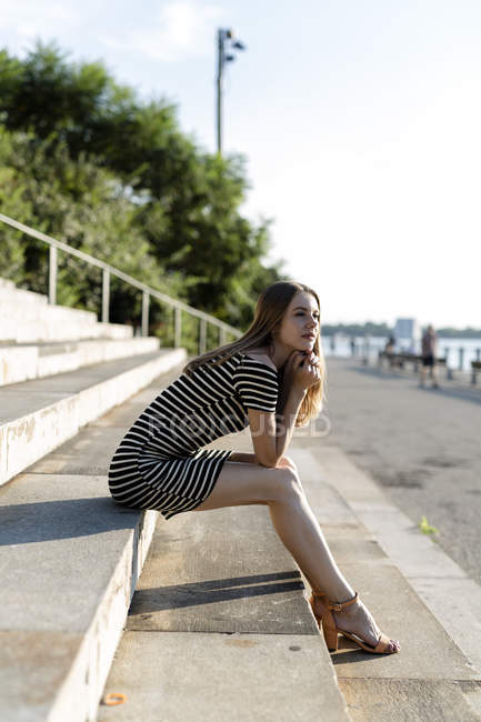 USA, New York, Brooklyn, giovane donna che si rilassa sulle scale e si gode il tramonto — Foto stock