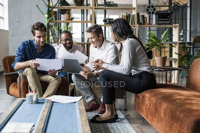 Бизнес-команда использует ноутбук и обсуждает документы в чердачном офисе — стоковое фото