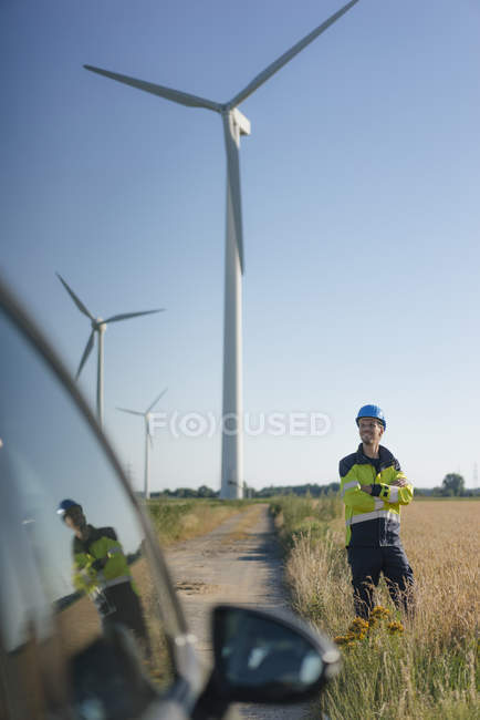Smiling engineer standing in a field at a wind farm — Stock Photo
