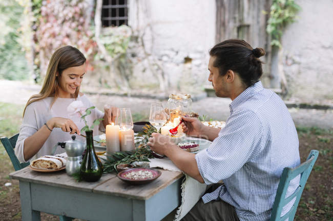Casal tendo uma refeição romântica à luz de velas ao lado de uma casa de campo — Fotografia de Stock