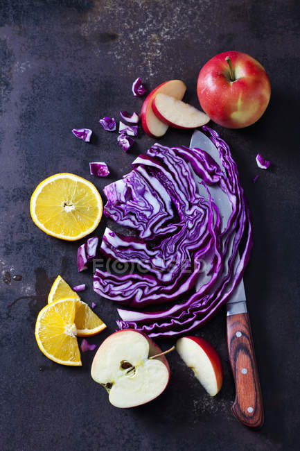 Rotkohl in Scheiben geschnitten, Äpfel und Orangenscheiben auf dunklem Grund — Stockfoto
