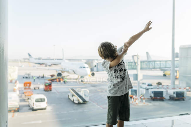 Spain, Barcelona airport, Boy in departure area, pretending to fly — Stock Photo