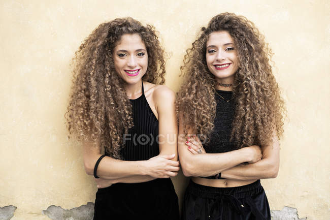 Portrait of laughing twin sisters standing side by side — Stock Photo