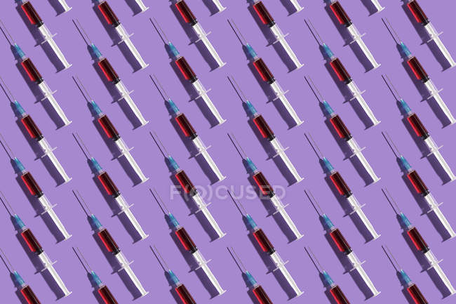 Несколько шприцев, организованных в узор на фиолетовом фоне — стоковое фото