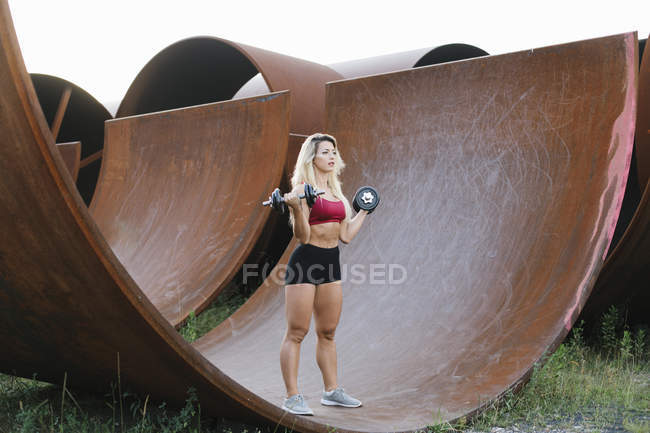 Спортивная женщина делает упражнения на вес на промышленной площадке — стоковое фото