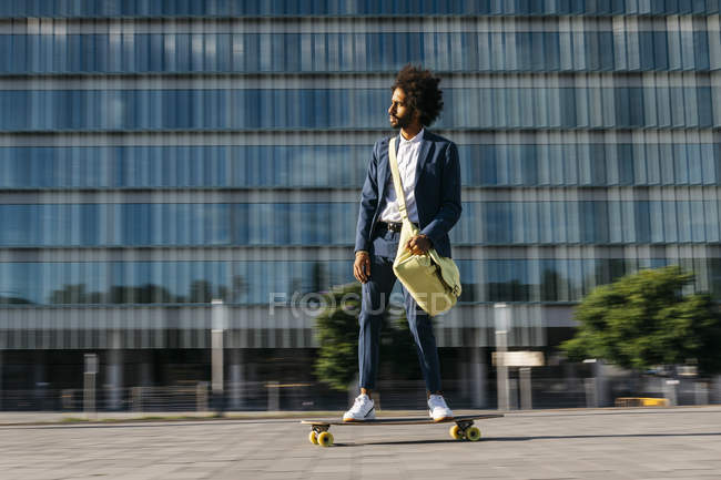 Spanien, Barcelona, junger Geschäftsmann fährt Skateboard in der Stadt — Stockfoto