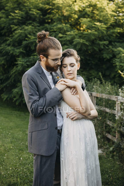 Sposa che abbraccia sposo su un prato — Foto stock