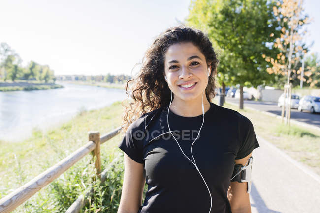 Porträt einer lächelnden, sportlichen jungen Frau am Flussufer — Stockfoto