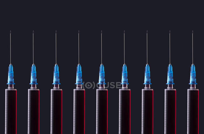 Multiple syringes organized in a pattern over dark background — Stock Photo