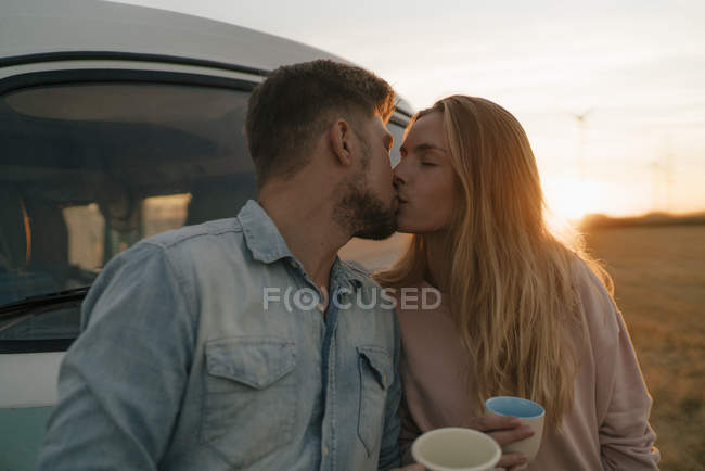 Pareja joven besándose en autocaravana en paisaje rural - foto de stock