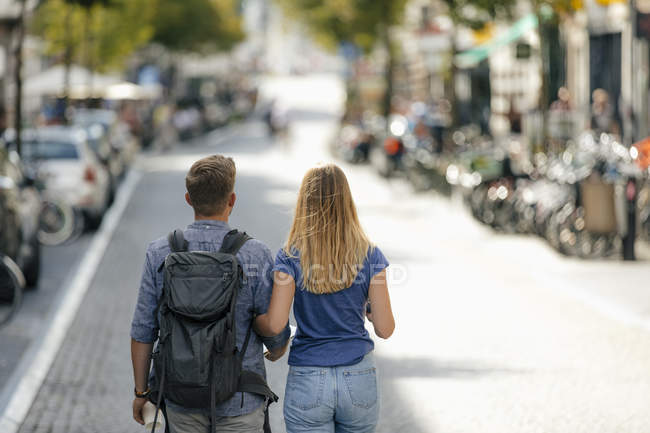 Нидерланды, полоса, вид сзади молодой пары, идущей по городской дороге — стоковое фото