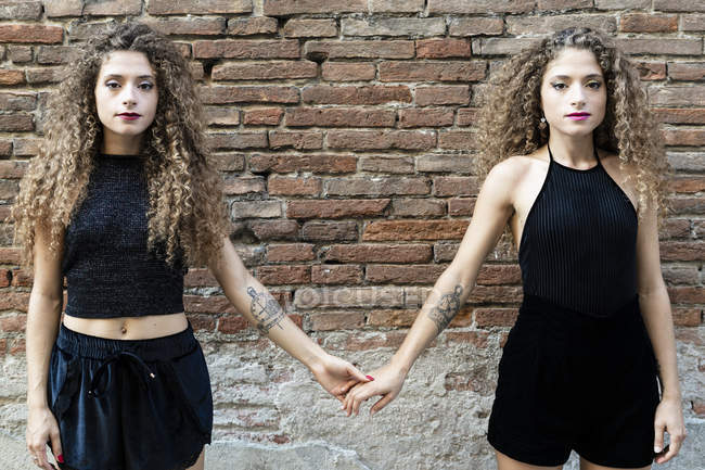 Portrait of twin sisters dressed in black holding hands — Stock Photo