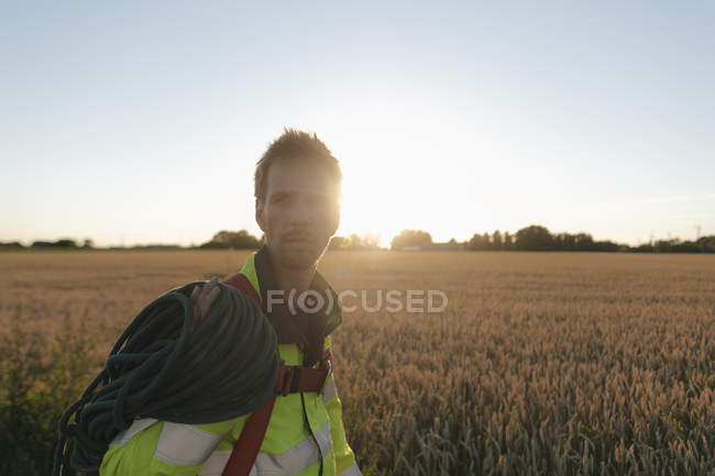Technician with climbing equipment at a field in sunset — Stock Photo