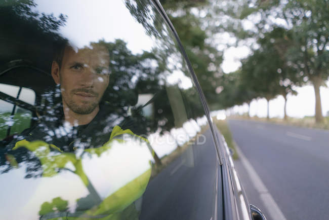 Portrait of man in protective workwear in a car at country road — Stock Photo