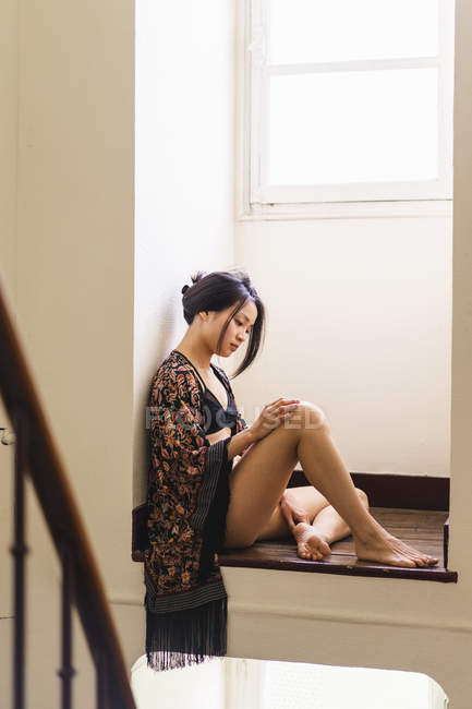Attraktive junge Frau in Dessous sitzt in einer Nische am Fenster — Stockfoto