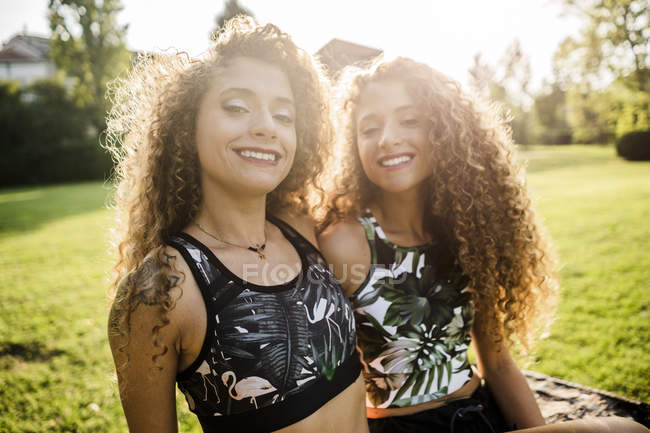 Portrait of smiling twin sisters at backlight — Stock Photo