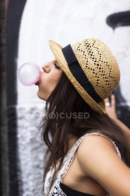Profil einer jungen Frau, die rosa Kaugummi pustet — Stockfoto