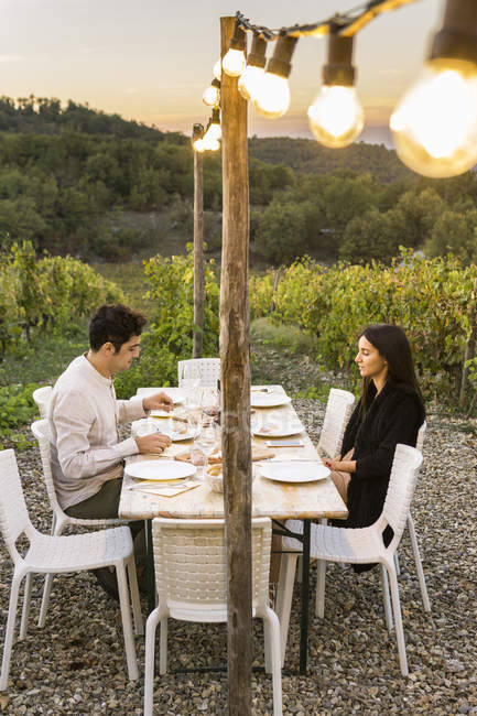 Italy, Tuscany, Siena, young couple having dinner in a vineyard — Stock Photo