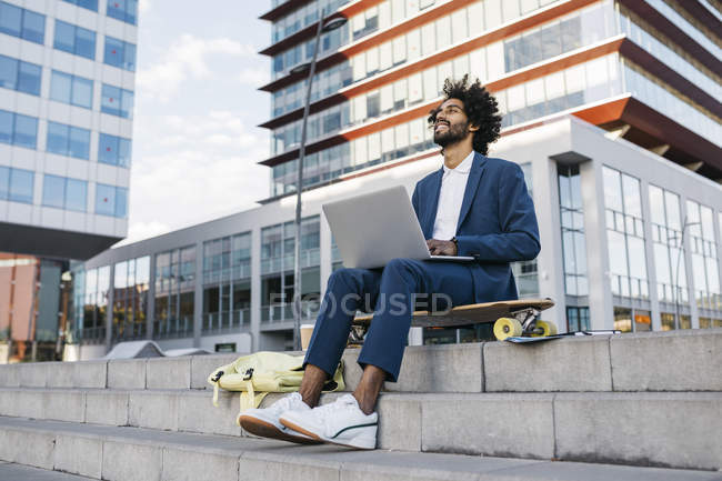 Испания, Барселона, молодой бизнесмен, сидящий в городе и работающий на ноутбуке — стоковое фото
