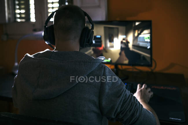 Young man sitting at his PC, playing computer games — Stock Photo