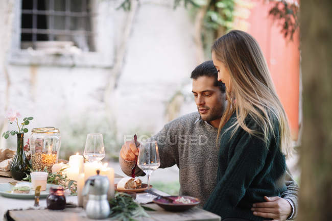 Casal romântico tendo uma refeição à luz de velas na mesa de jardim — Fotografia de Stock