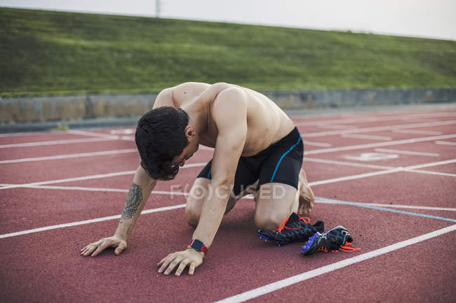 Atleta inginocchiato su una pista di tartan dopo aver terminato una gara — Foto stock