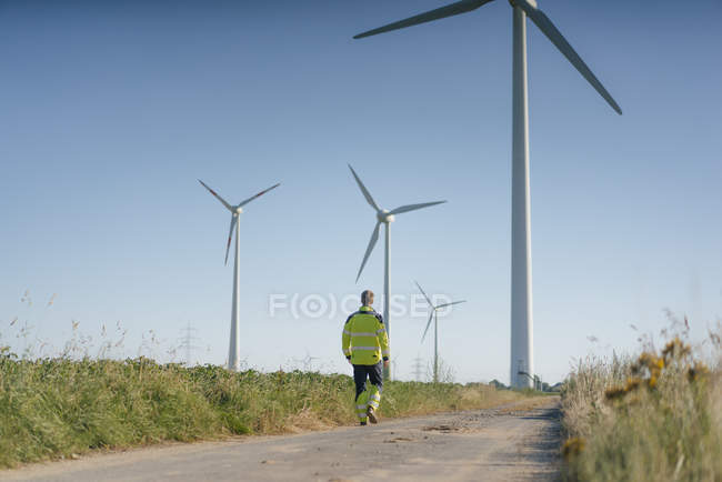 Engineer walking on field path at a wind farm — Stock Photo