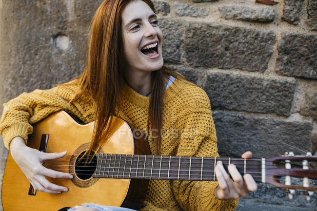 Руда жінка грає на гітарі в місті — стокове фото