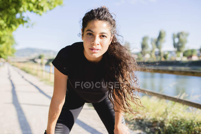 Retrato de uma jovem esportiva fazendo uma pausa na beira do rio — Fotografia de Stock
