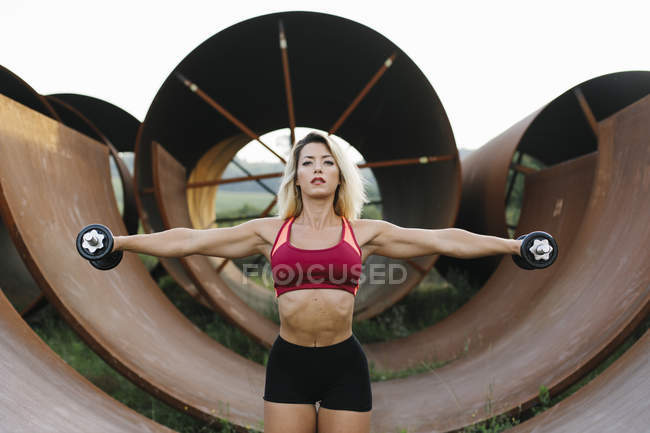 Mujer atlética haciendo ejercicio de peso en el sitio industrial - foto de stock