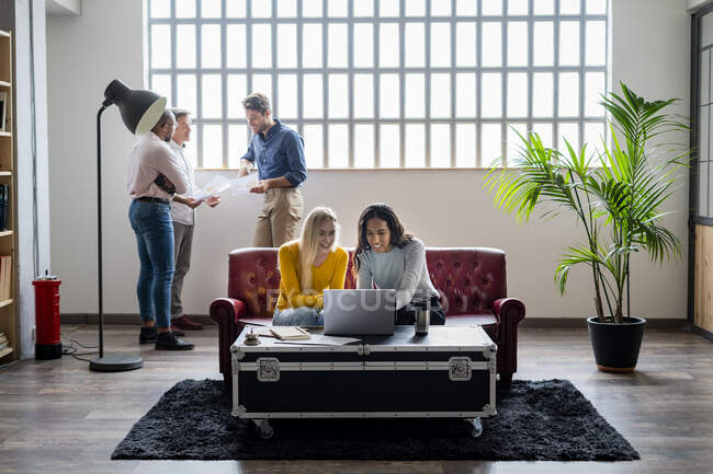 Business team using laptop and discussing documents in loft office — Stock Photo