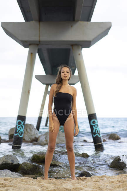 Retrato de una hermosa joven con traje de baño y de pie en el paseo marítimo - foto de stock