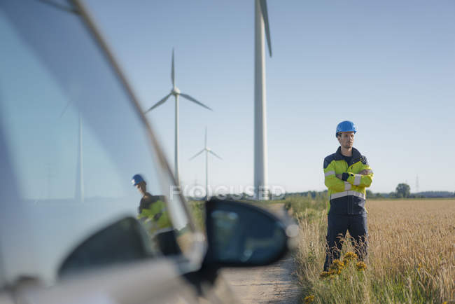 Инженер, стоящий в поле на ветряной электростанции — стоковое фото