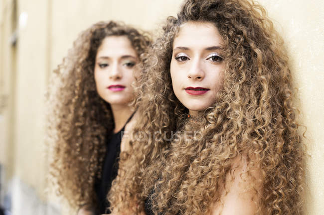 Portrait of young twin sisters near wall — Stock Photo