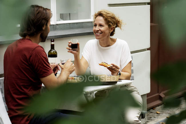 Glückliches Paar sitzt im Garten, isst Pizza, trinkt Wein — Stockfoto